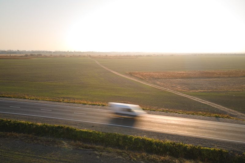 Aerial view of blurred fast moving cargo van driving on highway hauling goods. Delivery transportation and logistics concept.